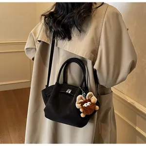 Details der schwarzen Leder-Dumpingtasche mit Schnalle und braunem Plüschtier-Anhänger