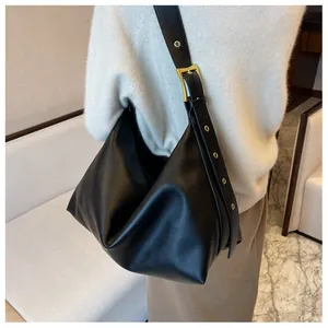 Detail of adjustable wide shoulder strap with golden metal eyelets on black hobo bag