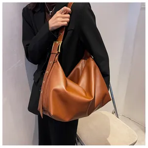 Detail of caramel brown hobo bag featuring adjustable shoulder strap and gold metal buckle