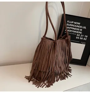 Detail of a large brown suede tote bag featuring multi-layered long fringes and leather straps