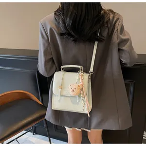 Back view of a light green crocodile pattern handbag with bear charm and silk scarf