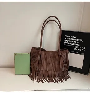 Detailed view of brown suede tote bag with fringe and a tablet showing its large capacity
