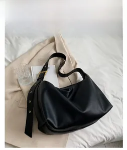 Close-up of black litchi grain leather hobo bag with adjustable gold-buckle strap