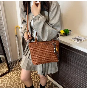 Brown woven texture tote bag with adjustable strap and wooden bead charm detail