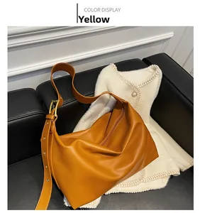 Detail of caramel yellow leather shoulder bag with adjustable strap on a dark sofa