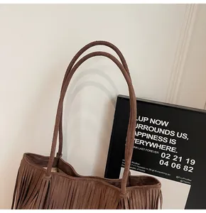 Detail of brown suede tote bag featuring bohemian fringes and slender shoulder straps