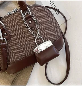 Detail of vintage shell bag showing herringbone fabric, leather trim, and lock charm