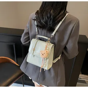 Detail of mint green PU leather backpack with teddy bear charm and embossed logo