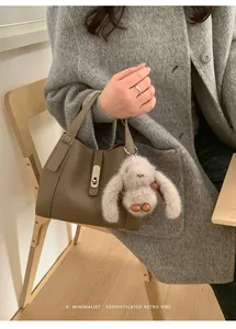 Detail of lychee pattern leather tote with metal turn-lock and plush bunny charm