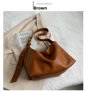 Close-up of a brown minimalist leather tote bag with a wide adjustable shoulder strap