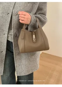 Close-up of brown lychee grain leather handbag featuring a silver twist lock buckle detail