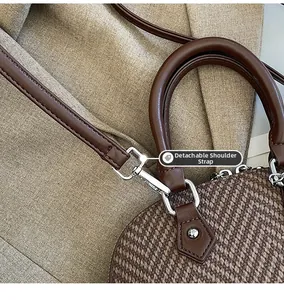 Detail of silver metal buckle and detachable brown leather strap on textured handbag