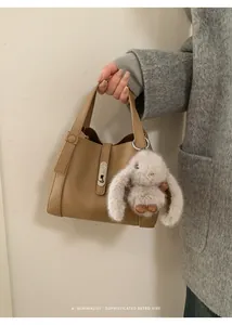 Detail of camel leather handbag with metal turn-lock and cute plush rabbit charm