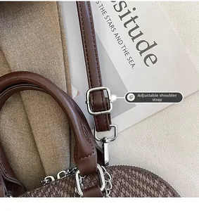 Detail view of adjustable leather shoulder strap and silver metal buckle on brown bag