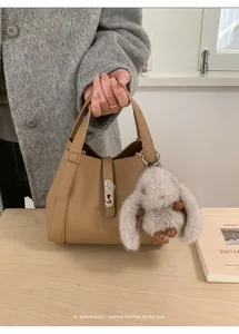Close-up of camel lychee pattern tote bag with silver lock and grey rabbit plush pendant