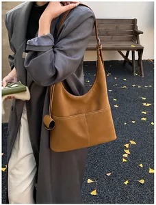 Detail of camel suede tote bag with white contrast stitching in an autumn outdoor setting
