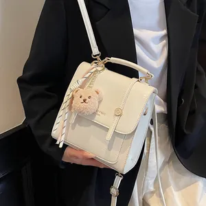 White faux leather minimalist backpack with a cute bear charm for daily commuting