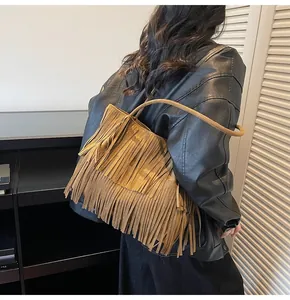 Detail of bohemian fringe shoulder bag in brown suede shown on a model