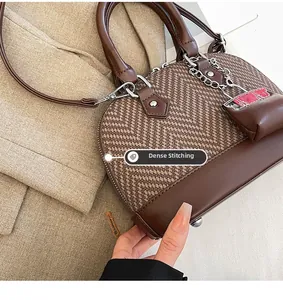 Detail of precise stitching on vintage shell bag with brown houndstooth and leather trim