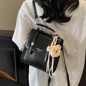 Black crocodile embossed backpack with plush bear charm and top handle for women