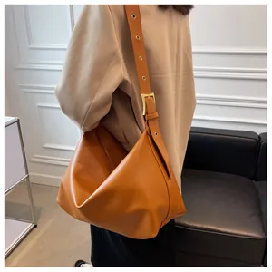 Detail of caramel faux leather bag with metal eyelet strap and golden buckle adjustment