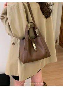 Detail of brown lychee grain leather bucket bag featuring a classic metal buckle closure