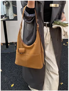 Detail of a brown leather hobo bag with contrast white stitching and matching bag charm