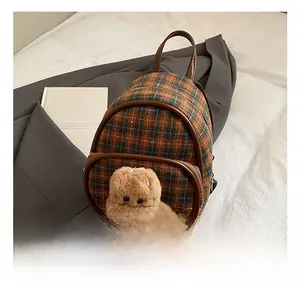Vue détaillée d'un mini sac à dos à carreaux avec tête d'ours en peluche et cuir