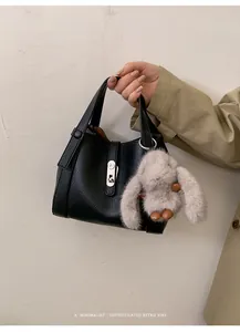 Close-up of black lychee leather handbag with silver twist lock and cute bunny charm