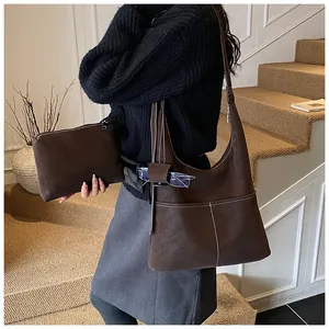 Detailed view of brown matte leather tote bag with white stitching and matching small pouch