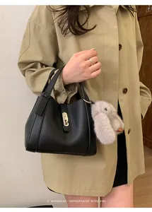Detail of black lychee grain leather bucket bag with silver buckle and plush rabbit charm