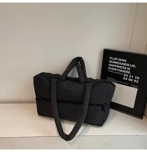 Detail of black quilted puffer tote bag with soft texture and padded shoulder straps