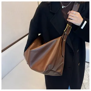 Detailed view of brown hobo bag with wide strap and large gold buckle on model