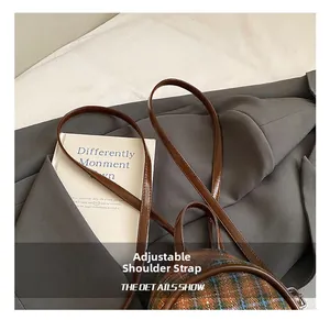Détail de la bandoulière réglable en cuir marron sur le mini sac à dos à carreaux
