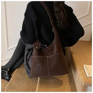 Detail of deep brown tote bag featuring white contrast stitching and front pockets
