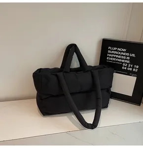 Detail of black quilted down tote bag with dual handles and puffy waterproof nylon texture