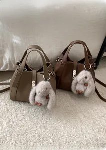 Detailed view of lychee pattern leather handbags with metal buckles and plush bunny charms