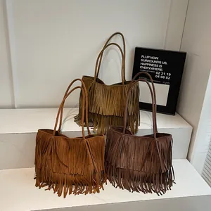 Three bohemian suede tassel tote bags in brown shades displayed on white stands