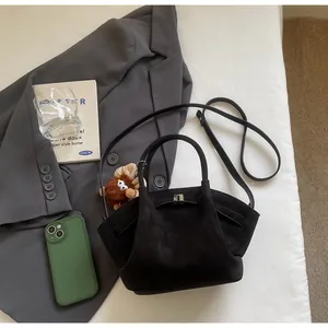 Makro-Detail der schwarzen Wildleder-Tasche mit silbernem Schloss und Plüsch-Anhänger Dekor