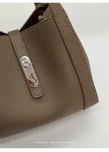 Detail view of elephant grey lychee grain leather with silver metal lock on the luxury handbag