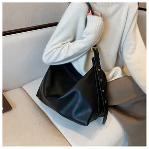 Detail of black tote bag featuring a wide shoulder strap and gold square buckle adjustment