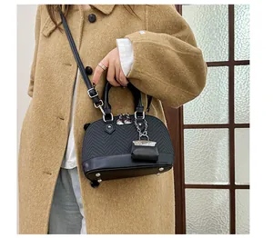 Detail of a black woven shell bag with smooth leather base and mini purse charm