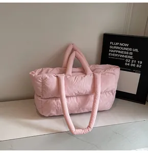 Detail of pink quilted puffer tote bag with dual shoulder straps on a marble surface