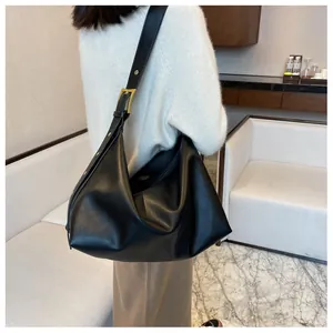Detail of black pebbled leather tote bag with adjustable strap and gold metal buckles