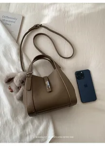 Detail of coffee brown pebble leather crossbody bag with silver twist lock and phone for scale