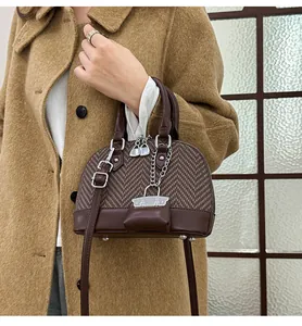 Detail of vintage shell bag showing brown plaid fabric texture and silver padlock charm