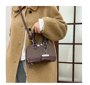 Close-up of brown leather shell bag with textured panels worn with a camel coat