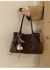 Gros plan d'un sac cabas rétro en daim marron foncé avec charme coeur léopard