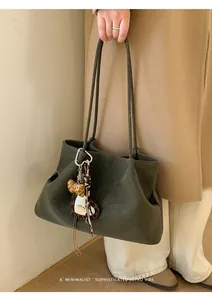 Détail du sac cabas en daim vert foncé avec un charmant pendentif cœur à motif léopard