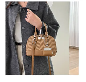 Detail of vintage patchwork shell bag with woven fabric texture and metal chain charm
